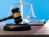 Gavel and scales of justice beside a laptop against a blue background
