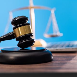 Gavel and scales of justice beside a laptop against a blue background