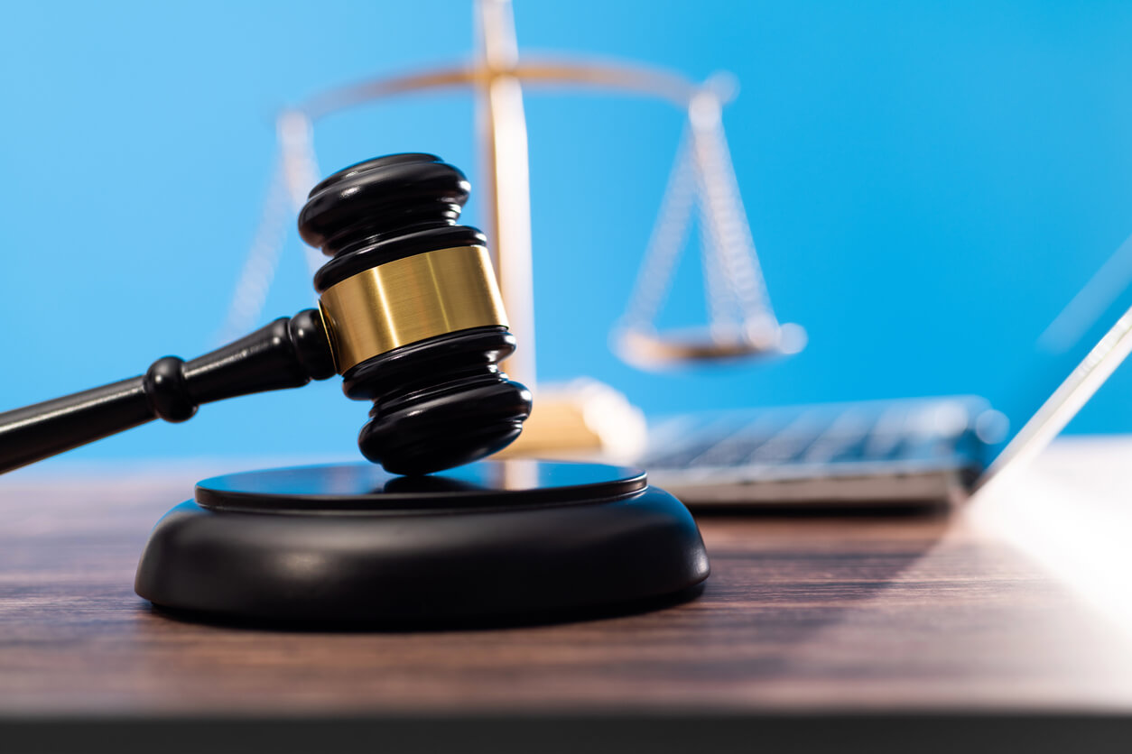 Gavel and scales of justice beside a laptop against a blue background