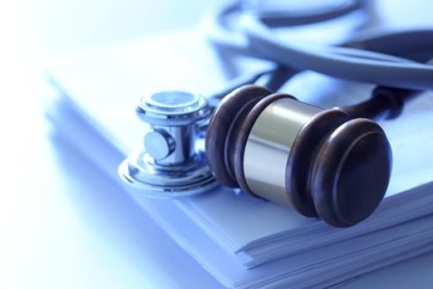 Gavel and stethoscope on stack of papers