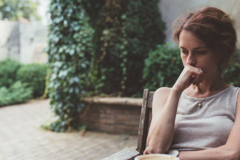 Depressed woman drinking coffee at the veranda