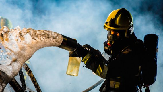 Firefighter extinguishing car fire with foam spray