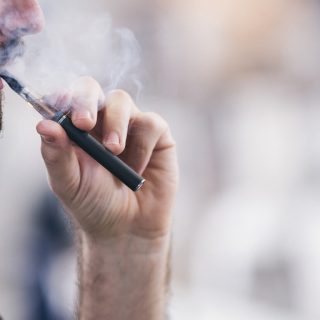 Man vaping from an e-cigarette device