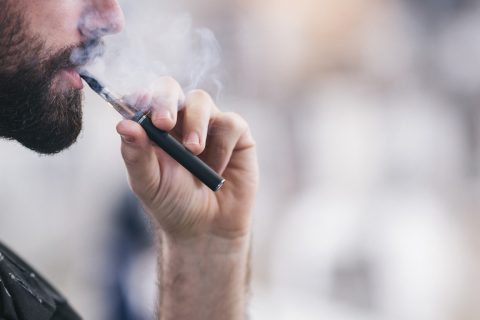 Man vaping from an e-cigarette device