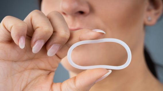 Woman holding plastic ring birth control