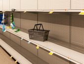 an empty shopping basket sits on an empty shelf at the grocery store
