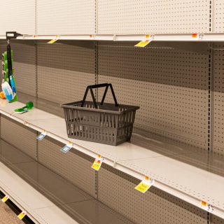 an empty shopping basket sits on an empty shelf at the grocery store