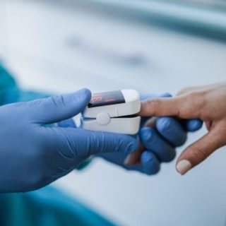 Health care professional using pulse oximeter on patient