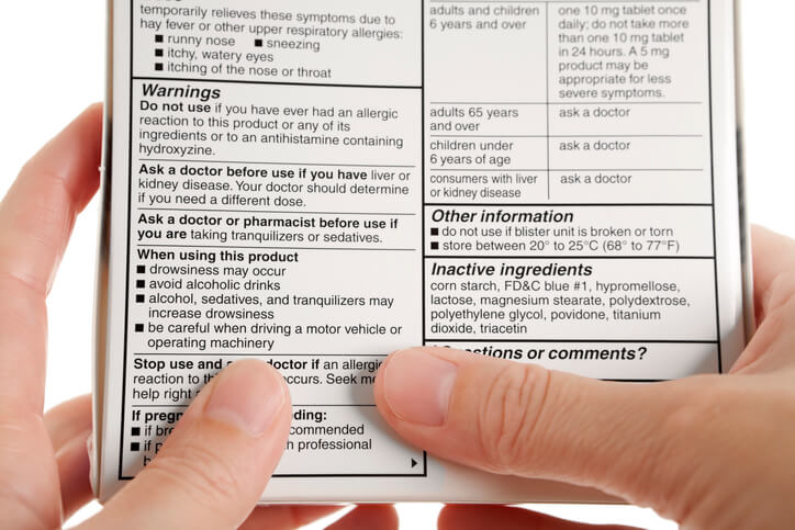 Person reading drug label on back of box