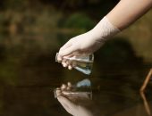 A researcher taking a sample of lake water.