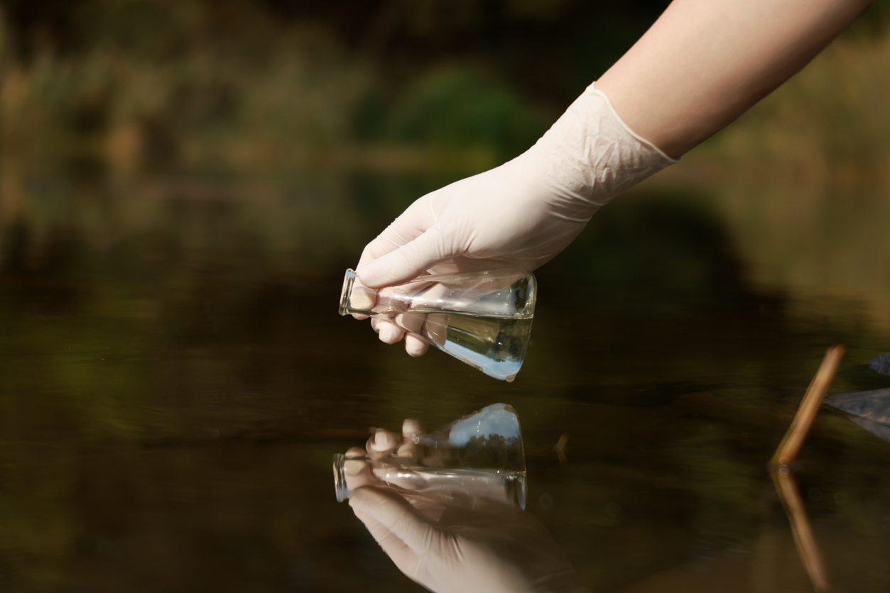 A researcher taking a sample of lake water.