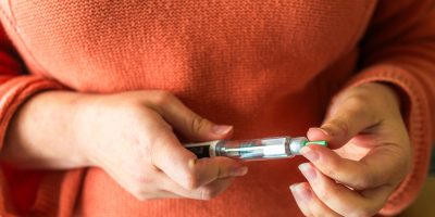 A woman holding an Ozempic pen near her stomach.
