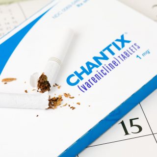 Broken cigarette on top of a pack of Chantix pills