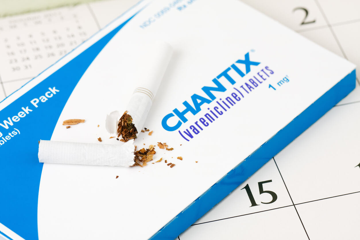 Broken cigarette on top of a pack of Chantix pills