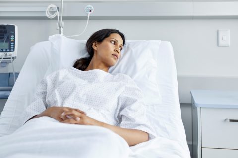 Woman in hospital bed wearing gown