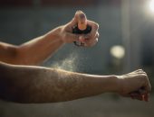 Woman spraying aerosol sunscreen on her arm