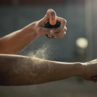 Woman spraying aerosol sunscreen on her arm