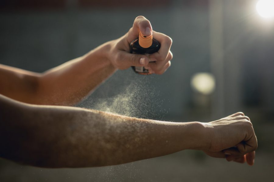 Woman spraying aerosol sunscreen on her arm