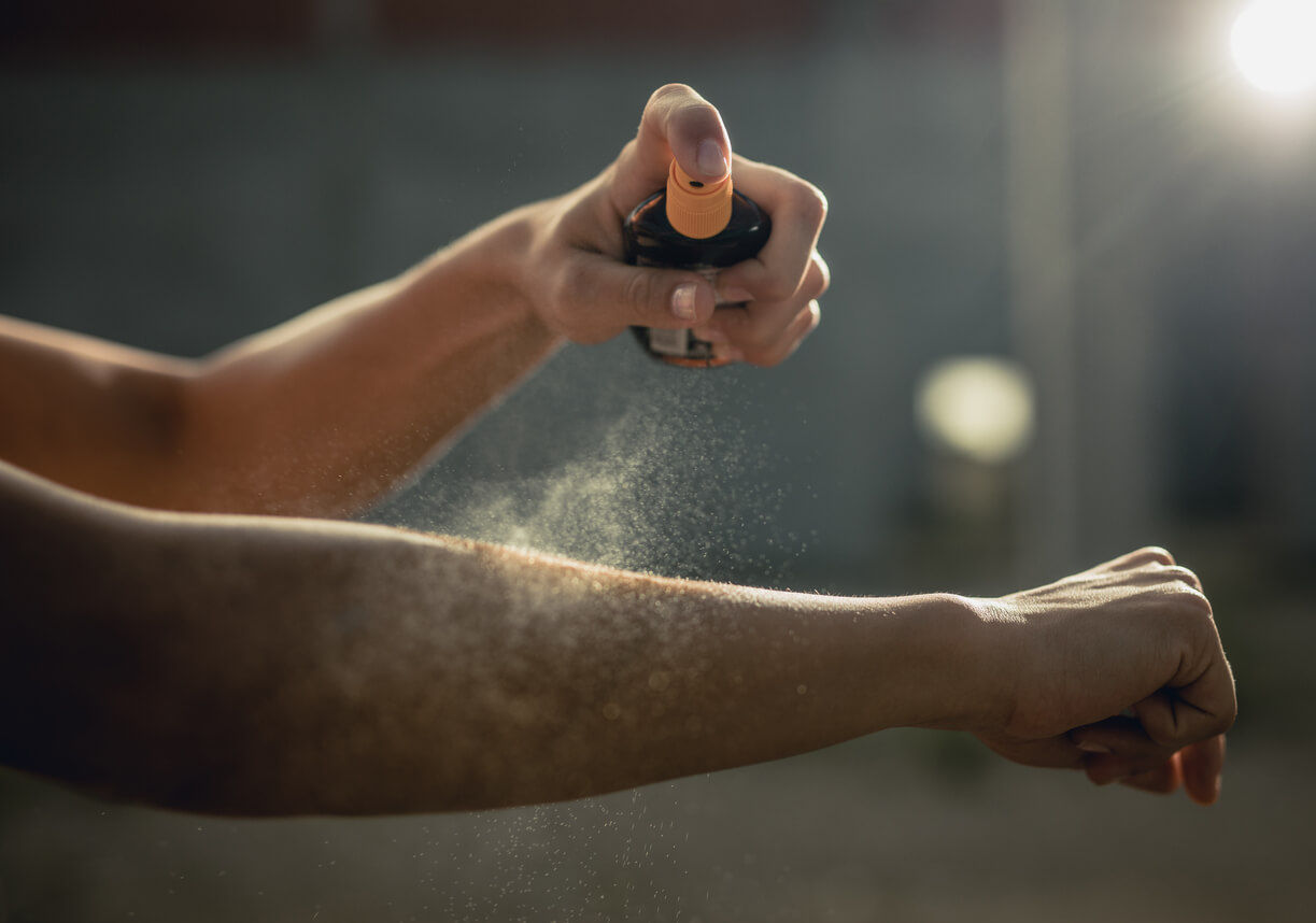 Woman spraying aerosol sunscreen on her arm