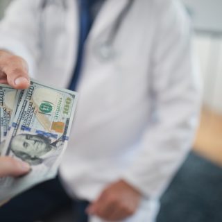 Doctor receiving cash from individual