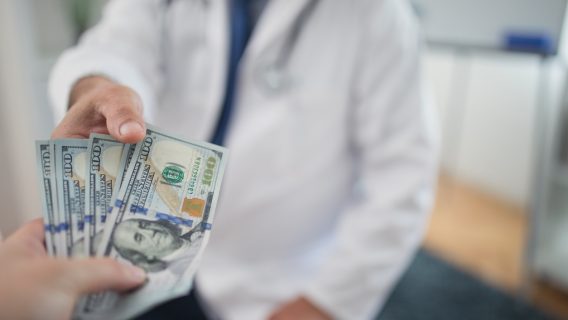 Doctor receiving cash from individual
