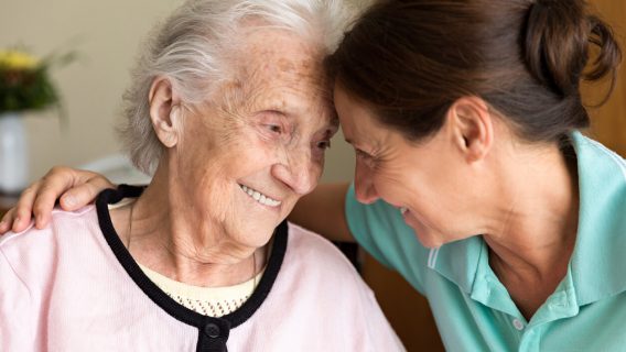 Caregiver and senior woman embracing