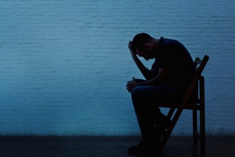 man sitting in chair with hand on head