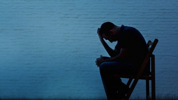 man sitting in chair with hand on head