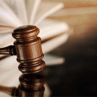 Open book and wooden gavel on table