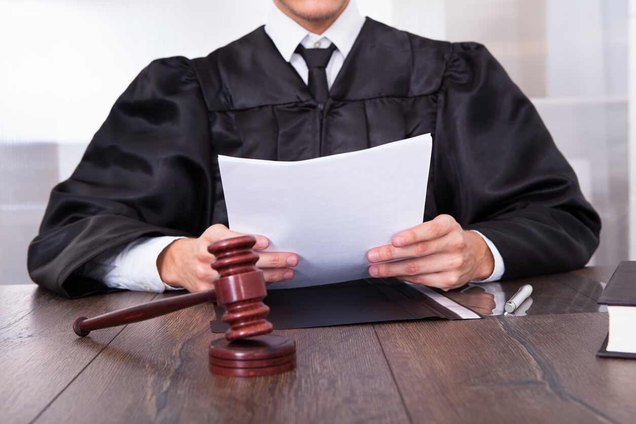 Judge holding documents with gavel on desk