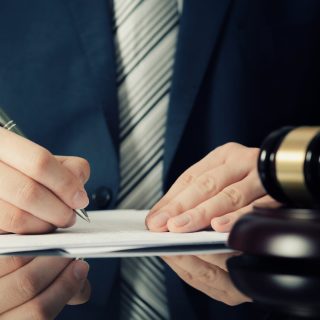 Man signing papers next to gavel