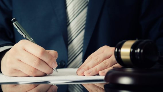 Man signing papers next to gavel