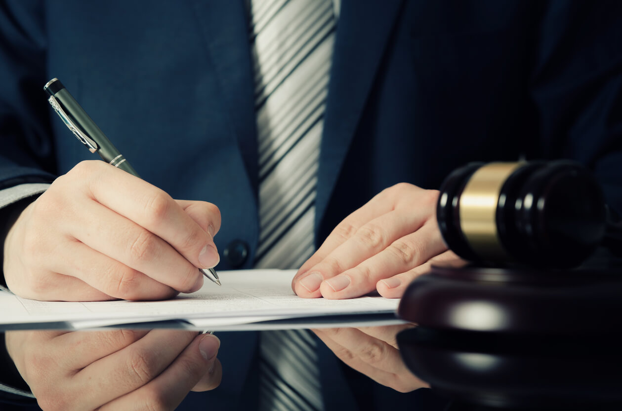 Man signing papers next to gavel