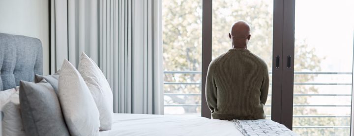 Man sitting on bed and staring out window