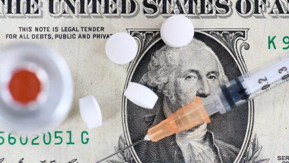 Syringe and pills on dollar bill