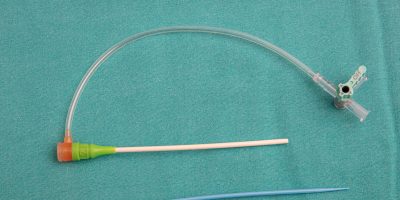 Introducer sheath kit with side-arm tubing, dilator, and puncture needle on a surgical drape