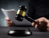 Judge raising a gavel while holding a court document