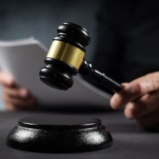 Judge raising a gavel while holding a court document