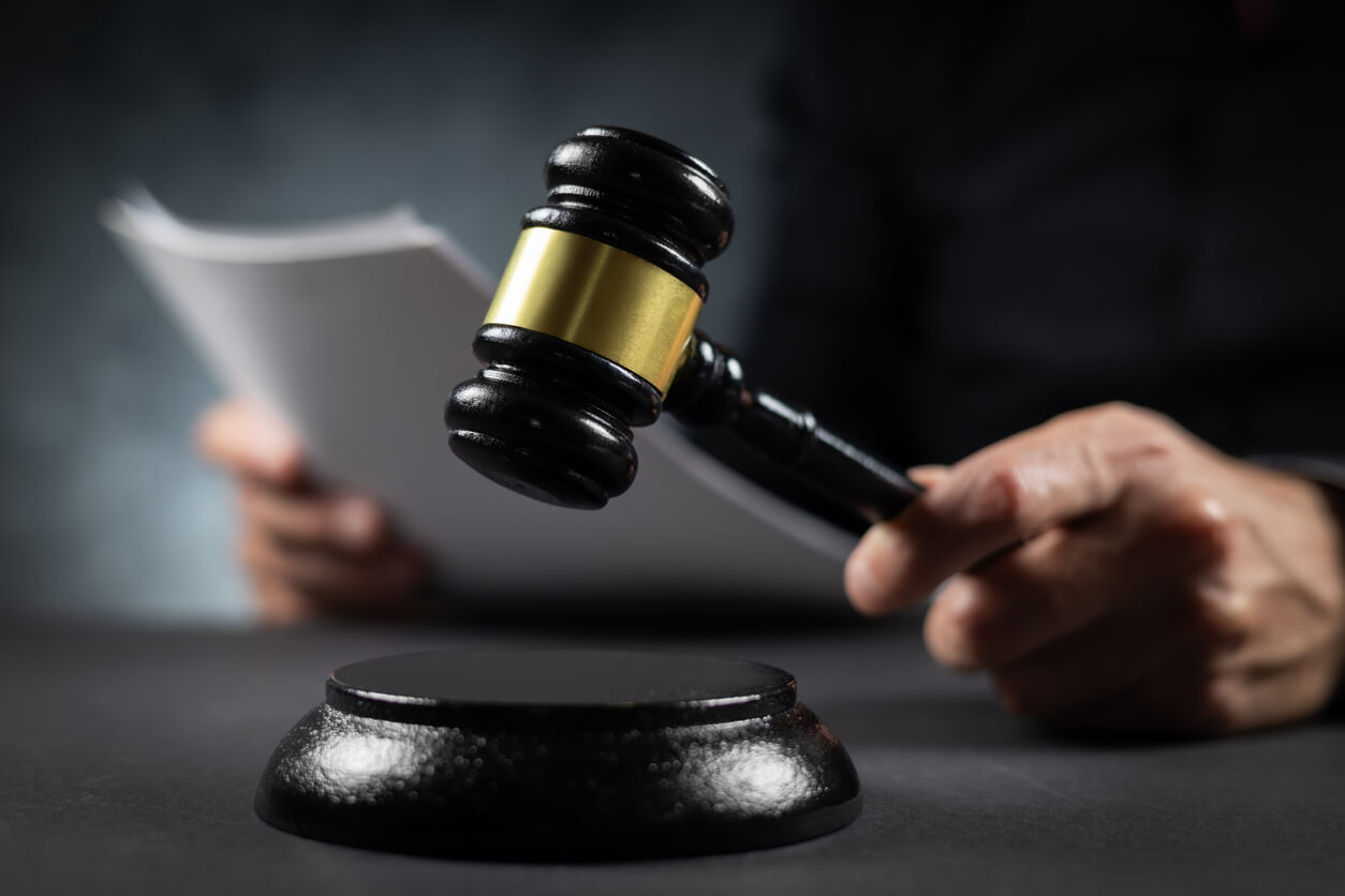 Judge raising a gavel while holding a court document