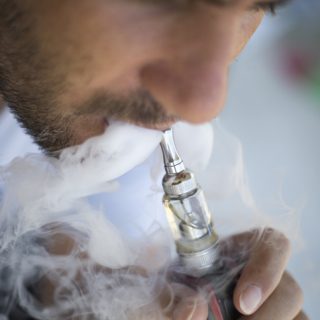 Man vaping on a gray background