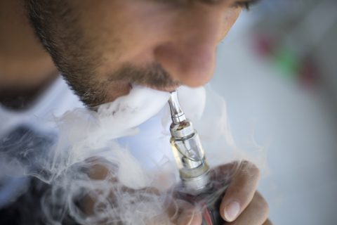 Man vaping on a gray background