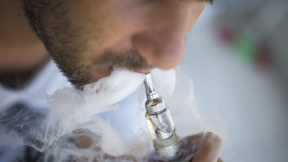 Man vaping on a gray background