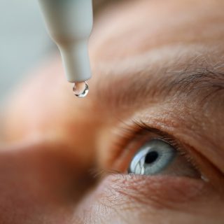 man using eye drops