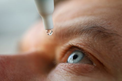 man using eye drops