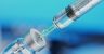 Medical disposable syringe for vaccine injection and glass vial on blue blur background.