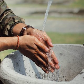Man in military uniform washing hands outdoors