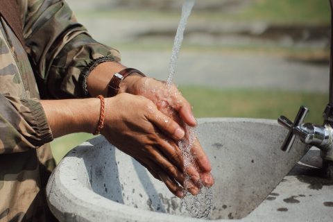 Man in military uniform washing hands outdoors