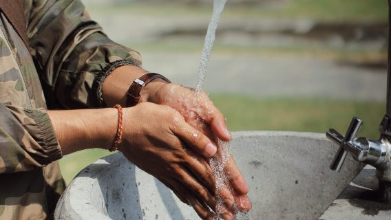 Man in military uniform washing hands outdoors