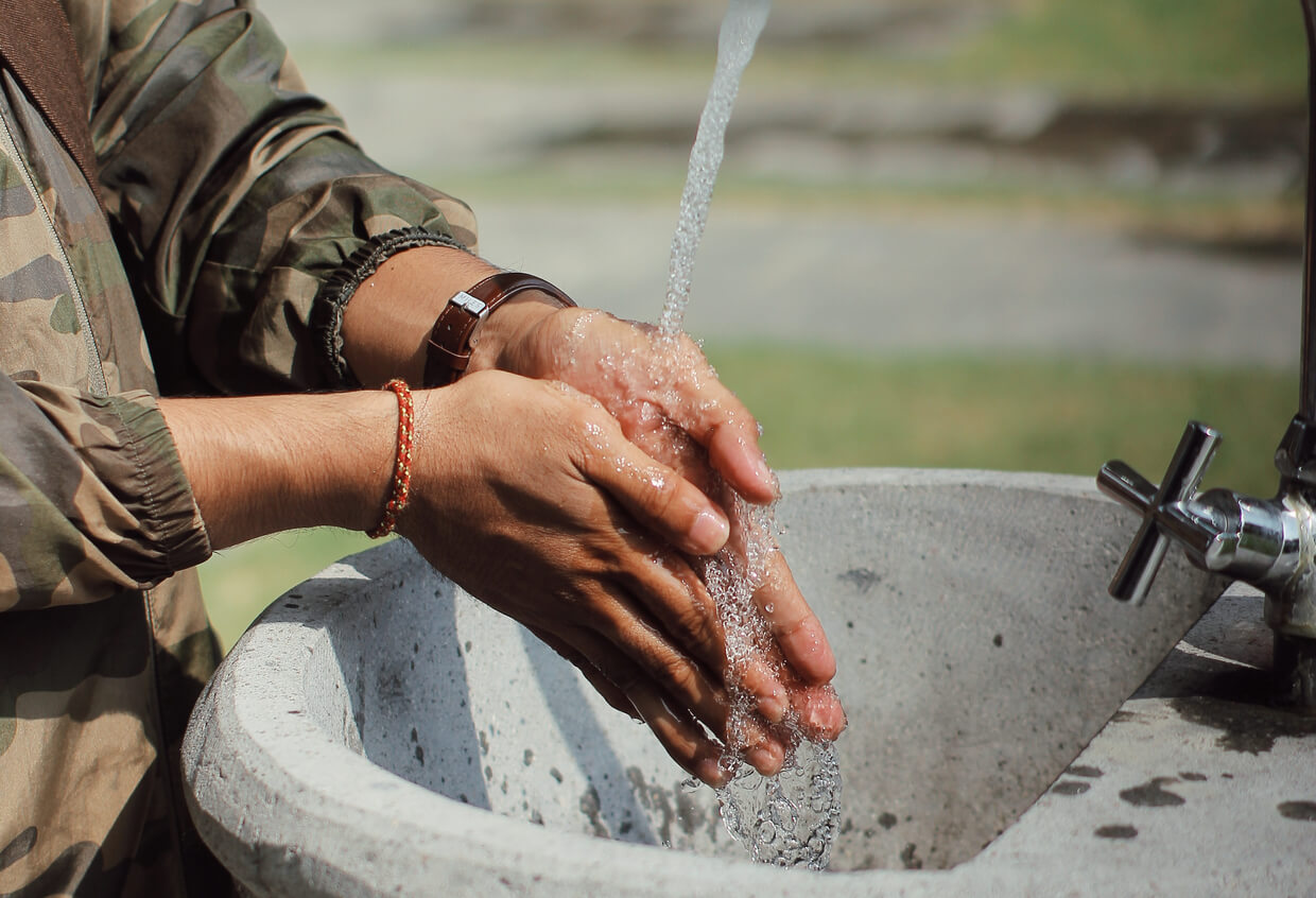 Man in military uniform washing hands outdoors