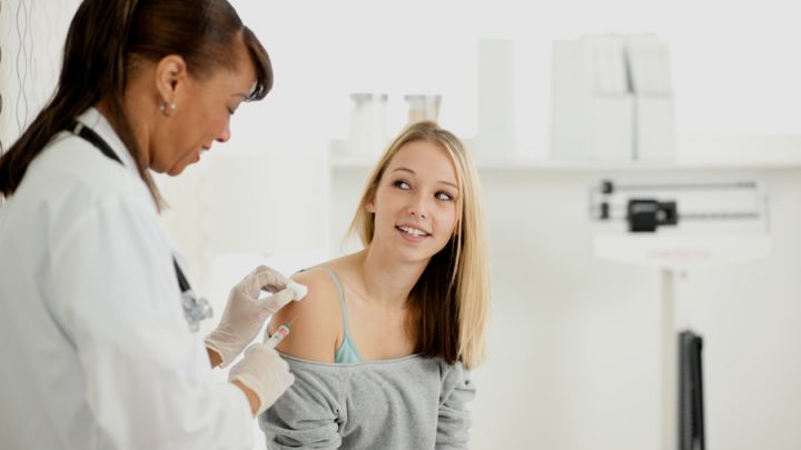 Teenage girl getting a shot in her shoulder